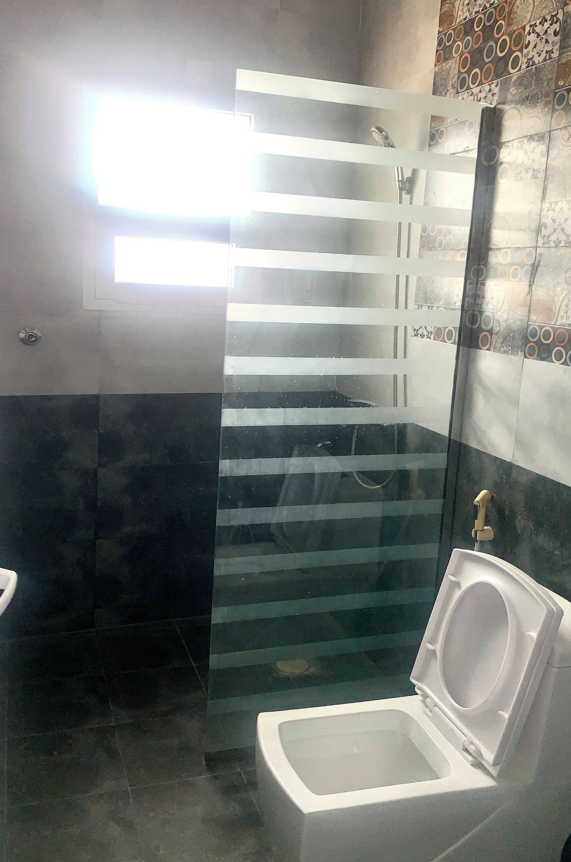 A bathroom with a glass shower enclosure, a toilet, and a sink.