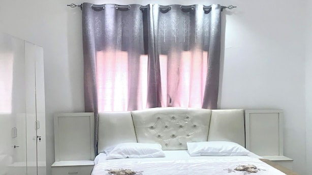 A bedroom with a bed, a ceiling fan, curtains, and a nightstand. - OYO 157 Dream Barka Hotel (Barka)