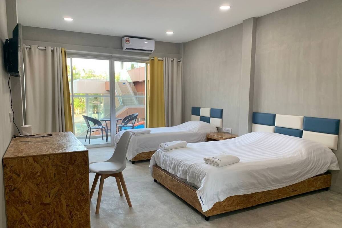 A hotel room with two beds, a desk, and a chair.