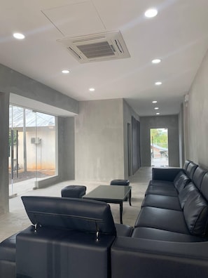 Un interior moderno con un sofá de cuero negro, una mesa de vidrio y un amplio ventanal con vistas al exterior.