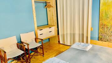 Una camera da letto con un'armadio in legno, un letto con lenzuola bianche, una sedia di legno e un quadro appeso al muro.