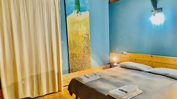 A bedroom with a bed, a nightstand, a painting on the wall, and a wooden ceiling.