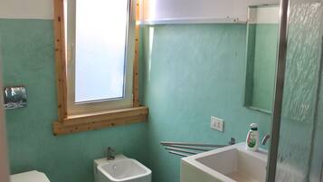 A bathroom with a window, a sink, a toilet, and a mirror.