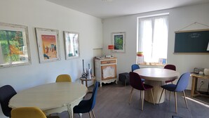 Uma sala de jantar com uma mesa redonda, cadeiras e obras de arte nas paredes.