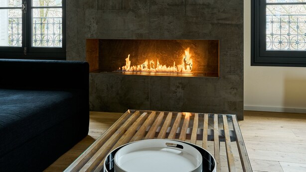 Una sala de estar moderna con chimenea, ventanas amplias y una mesa redonda.