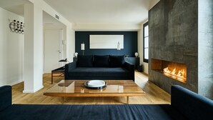Una sala de estar moderna con un sofá azul oscuro, una mesa de centro de vidrio y una chimenea.
