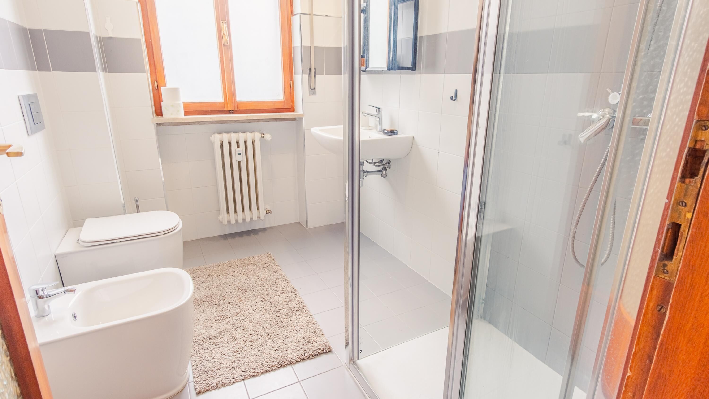 Une salle de bain moderne équipée de toilettes, d’un lavabo, d’une douche et d’une cabine de douche en verre.