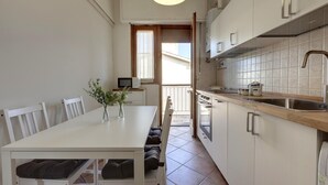 A compact kitchen with a dining area, featuring white cabinetry, a wooden countertop, and a built-in oven. - Colombo 76 in Firenze (Florence)