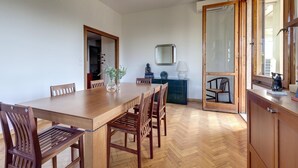 A dining area with a wooden table and chairs, a mirror on the wall, and a view through an open door. - Colombo 76 in Firenze (Florence)