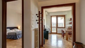 A hotel room with a bed, a radiator, a wooden floor, a dining area with a table and chairs, and a view through a glass door. - Colombo 76 in Firenze (Florence)