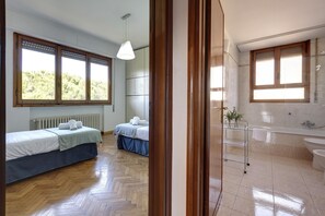 A bedroom with two beds, a wooden floor, and a window with a view of trees. - Colombo 76 in Firenze (Florence)