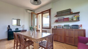 A dining area with a wooden table and chairs, a bookshelf with books, and a view through a doorway. - Colombo 76 in Firenze (Florence)