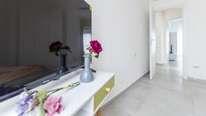 A modern room with a white console table, a mirror, and a vase with flowers.