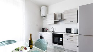 A modern kitchen with a washing machine, microwave, and refrigerator.