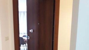 A hallway with a wooden door, a doormat, and a tiled floor. - Michael Apartments - Private Parking (Lefkada)
