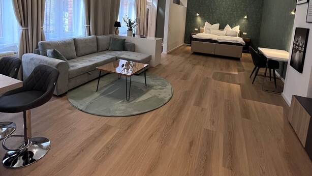 Un salon moderne avec un canapé d’angle, une petite table basse et un coin repas comprenant une table et des chaises.