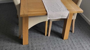 A dining table with four chairs, a white table runner, and two potted plants. - Impeccable 4-bed House in Leicester (Leicester)
