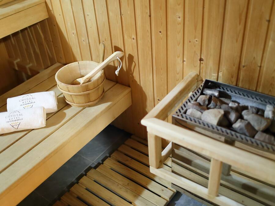 Un sauna en bois avec un banc en bois, un récipient en bois et une louche, ainsi qu’un plateau de pierres.