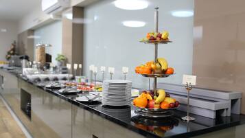 A buffet setup with various food items and a fruit display.