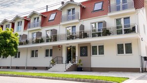 Un hôtel à plusieurs étages, doté de balcons, d’une entrée principale et d’une enseigne.