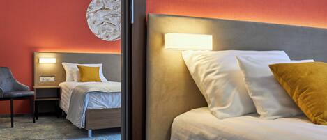 Habitación de hotel con dos camas, una silla, una mesita de noche y una lámpara fijada a la pared.
