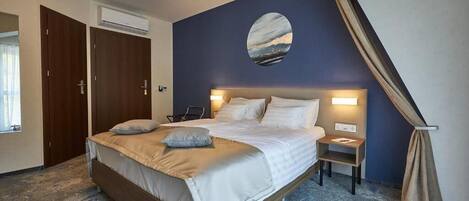 Un dormitorio con una cama, mesitas de noche, un adorno circular en la pared y una ventana.