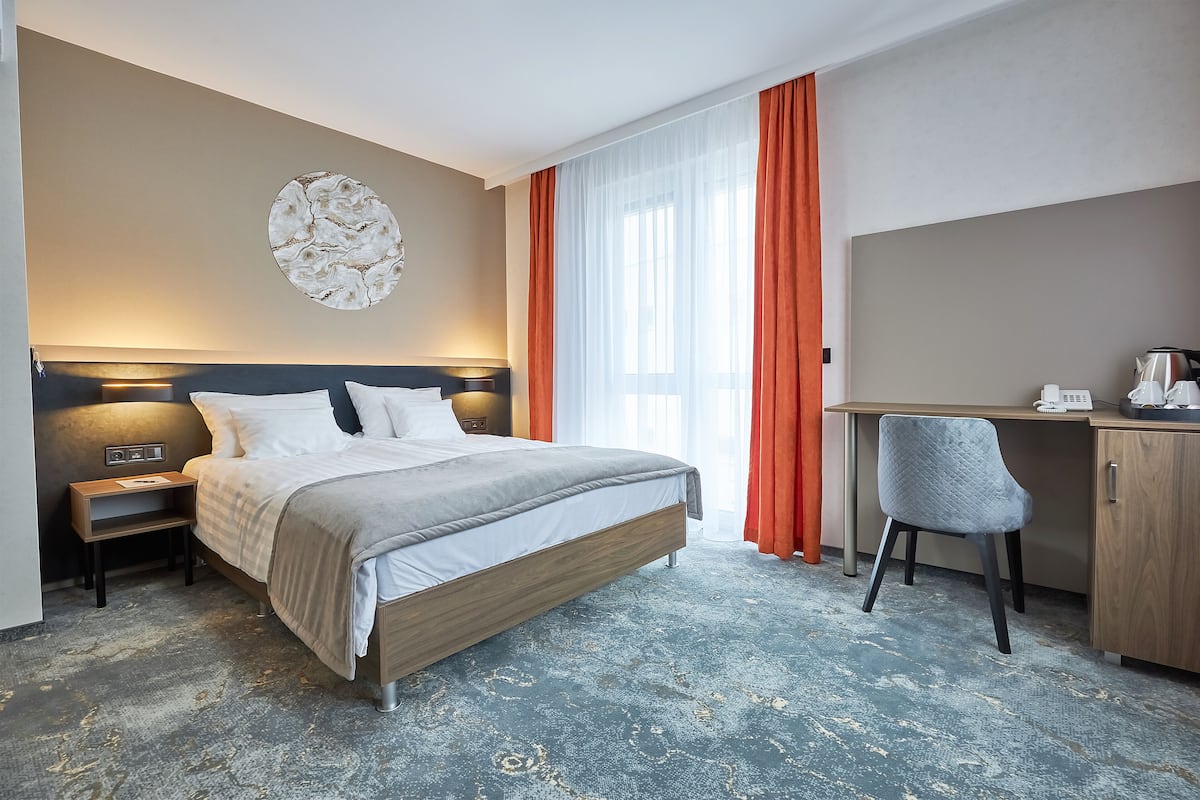 Une chambre d’hôtel équipée d’un lit, d’un bureau, d’une chaise et d’une œuvre d’art accrochée au mur.