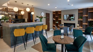 Un espace bar moderne avec un comptoir, des tabourets de bar jaunes et un téléviseur fixé au mur.