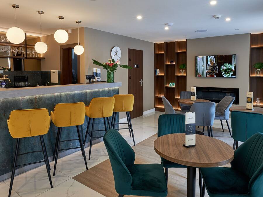 Een moderne bar met een toog, gele barkrukken en een aan de muur bevestigde televisie.