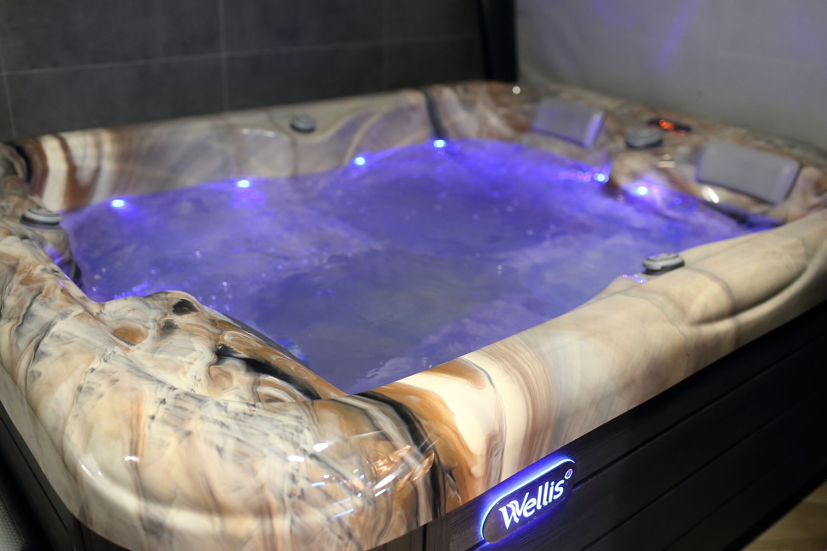 A hot tub with a marble-like exterior and a blue LED light.