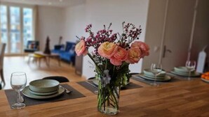 Een eettafel gedekt met borden, een bloevas en een wijnglas.