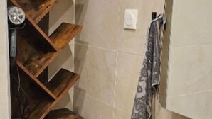Een badkamer met een houten wandplank, een zwarte wastafel en een spiegel.