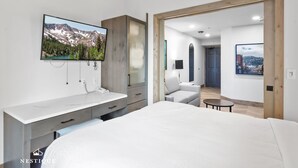A modern bedroom with a large bed, a TV mounted on the wall, a desk, and a chair. - Alpine Abode at Canyons Village | Ski-In/Out Condo (Park City)