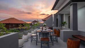 Une terrasse sur le toit, avec une table à manger pour deux, entourée de plantes en pot et de bancs en bois.