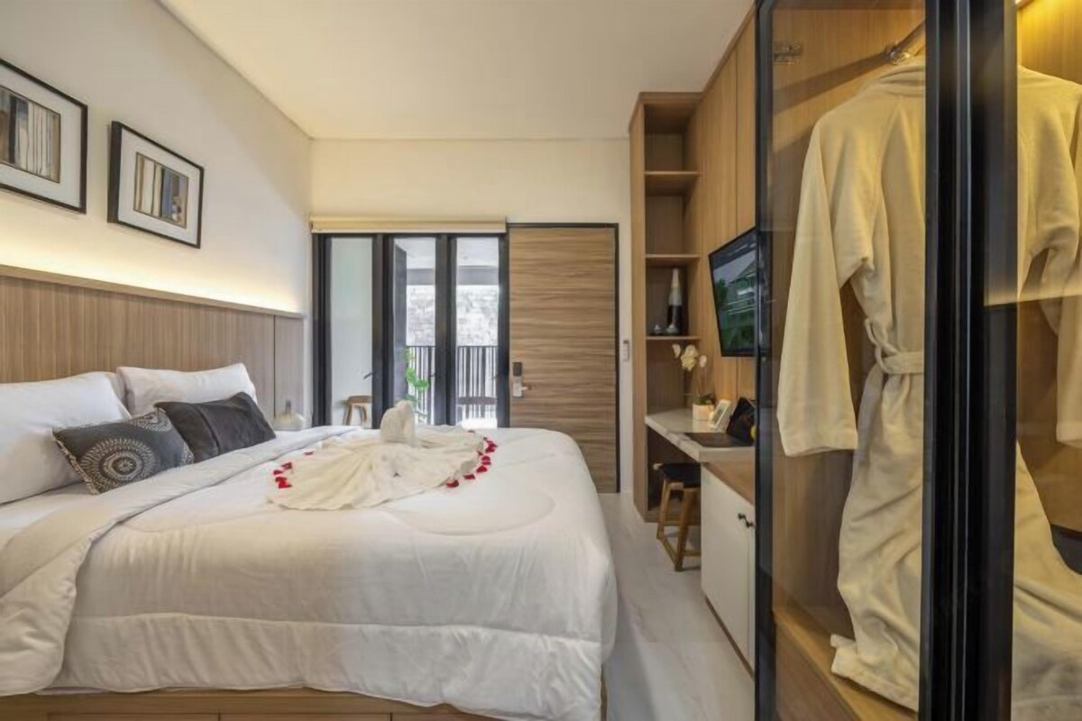 A modern bedroom with a large bed, a TV, and a walk-in closet.