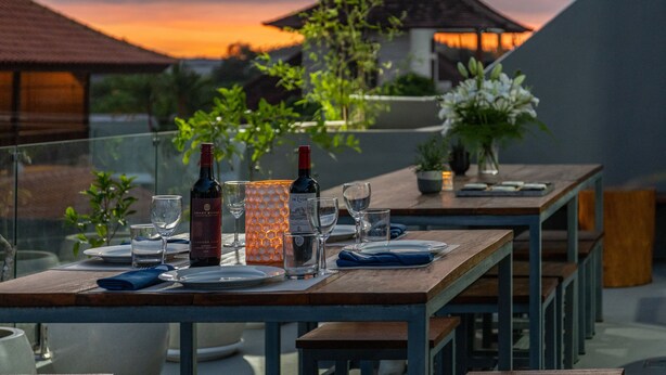 Une table dressée pour un dîner à deux, avec des verres à vin, une bouteille et une bougie.
