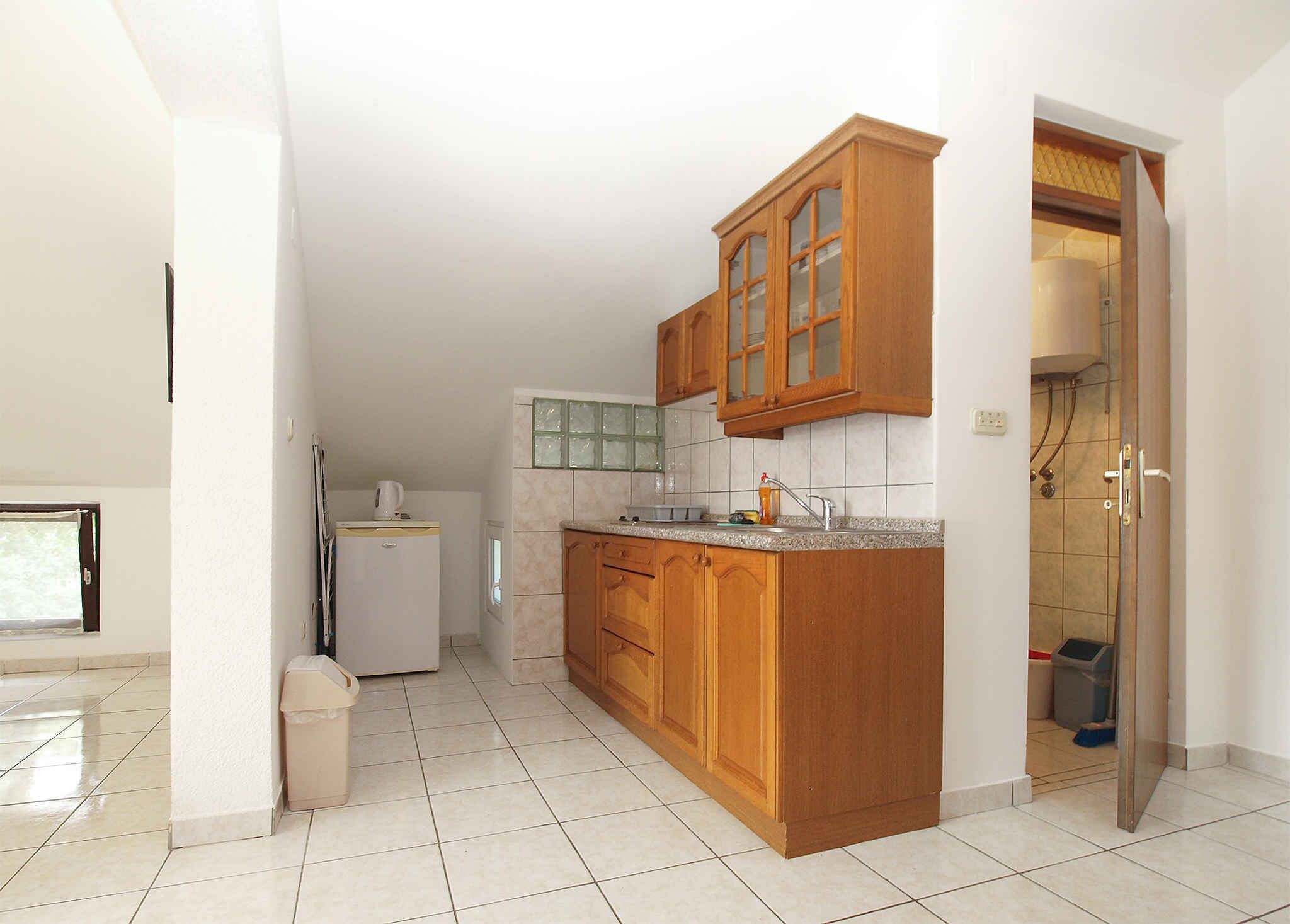A kitchen with wooden cabinets, a refrigerator, and a tiled floor.