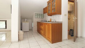 A kitchen with wooden cabinets, a refrigerator, and a tiled floor. - Holiday apartment with air conditioning (Banjole)