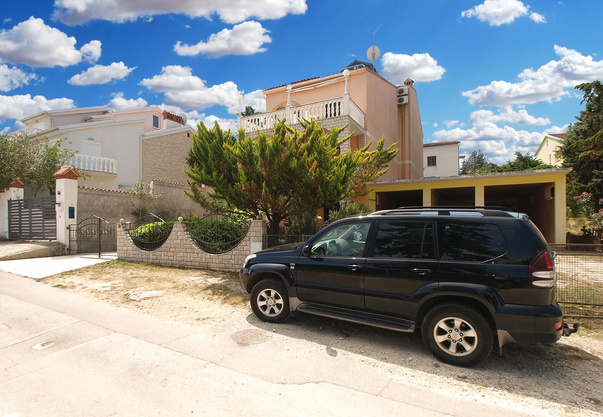 A black SUV parked in a driveway with a house in the background.