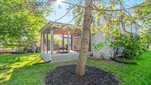 A covered patio with a table and chairs, surrounded by a tree and a house. - Downtown Three Oaks Home, Sleeps 6, Fire Pit, Walk to Shops (Three Oaks)