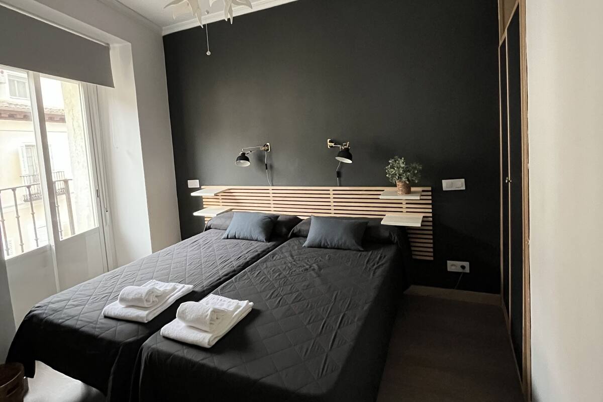 Un dormitorio moderno con una cama grande, lámparas de noche y una lámpara en el techo.
