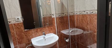 A bathroom with a glass-enclosed shower, a white sink, and a toilet.