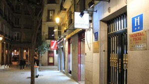Un couloir d’hôtel avec une enseigne indiquant « Hostal Tijical » et une autre enseigne, plus petite, indiquant simplement « Hostal », au-dessus de la porte.