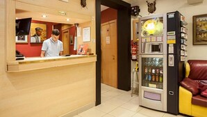 Un espace d’accueil comprenant un comptoir, un membre du personnel, un distributeur automatique et un canapé en cuir rouge.