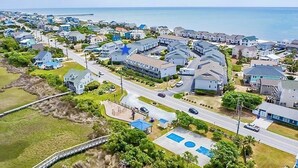 Ett flygbildsbild av ett bostadsområde vid kusten med hus, en strand och en pir.