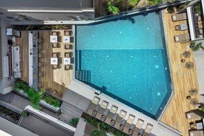 An aerial view of a rooftop pool area with a wooden deck, lounge chairs, and a dining area with tables and chairs. - Luuks Luxury Accommodation (Kassandra)