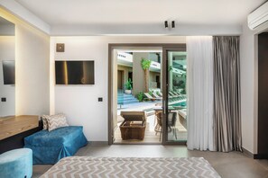 A modern hotel room with a large bed, a TV mounted on the wall, a balcony with a pool and lounge chairs, and a sliding glass door. - Luuks Luxury Accommodation (Kassandra)