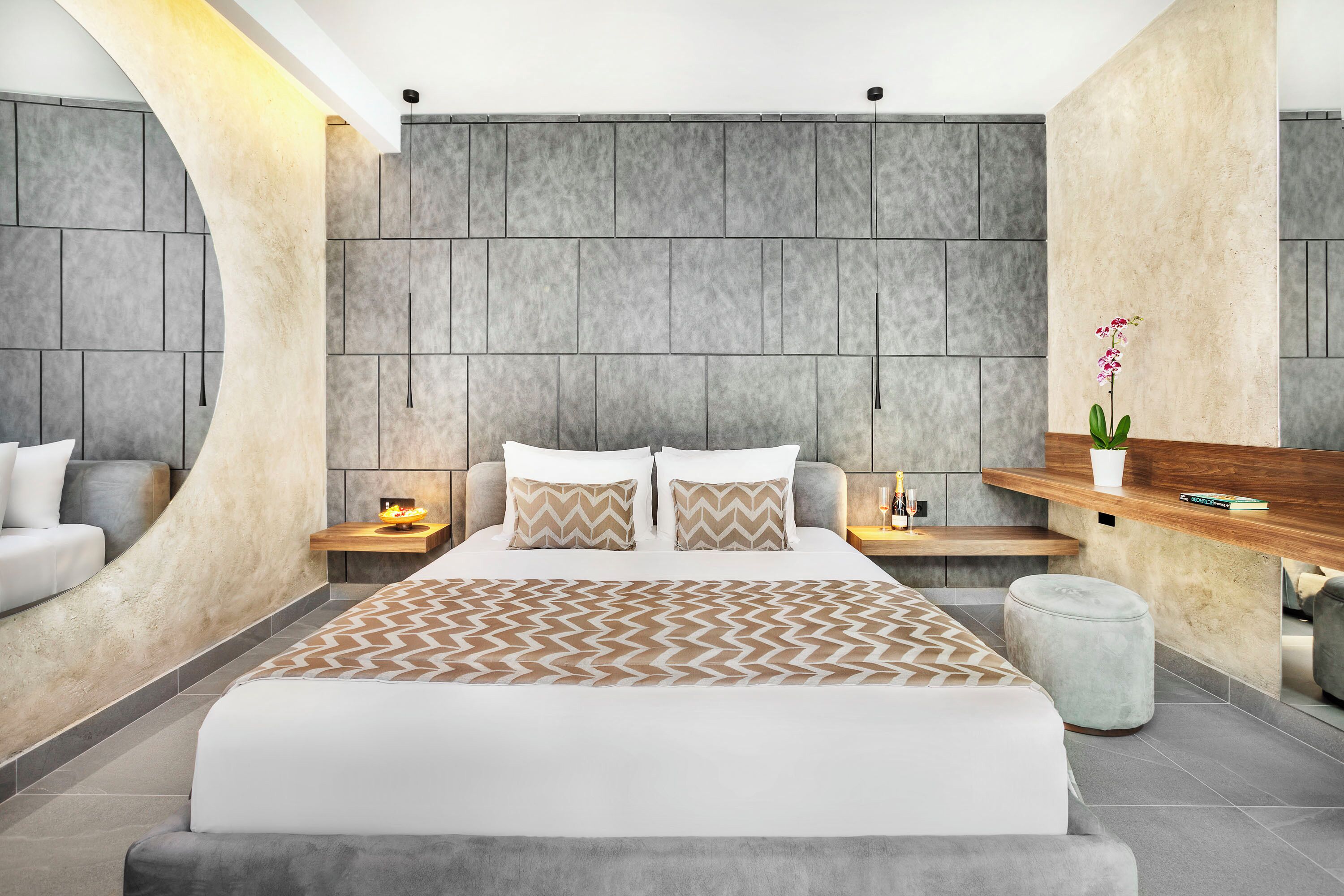 Ein modernes Schlafzimmer mit einem großen Bett, einer gewölbten Wand und einem Holzregal mit einer Topfpflanze.