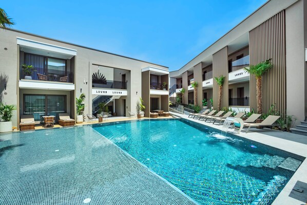 A modern hotel with a central swimming pool, lounge areas, and multiple balconies. - Luuks Luxury Accommodation (Kassandra)
