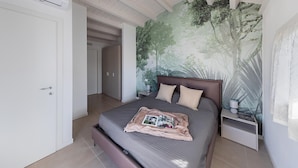 Une chambre à coucher avec un grand lit, une table de chevet, une fresque murale et une porte.
